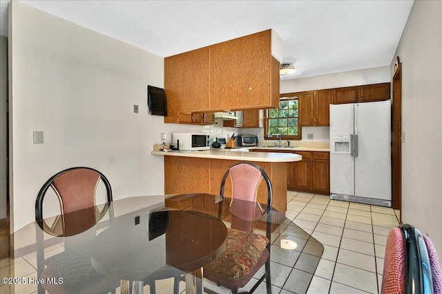 163 NW 9th St, Oak Island, NC 28465 - kitchen with white appliances, brown cabinetry, light countertops, a peninsula, and exhaust hood
