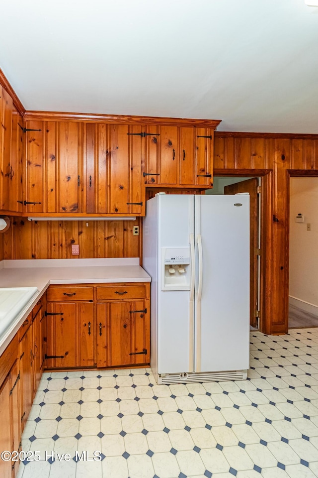 106 E New Hope Rd, Goldsboro, NC 27534 - kitchen featuring white fridge with ice dispenser, light flooring, light countertops, wooden walls, and brown cabinets
