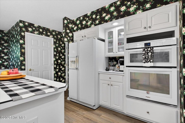 1610 Winding Way SW, Ocean Isle Beach, NC 28469 - kitchen featuring white appliances, wallpapered walls, white cabinetry, light wood-style flooring, and light countertops
