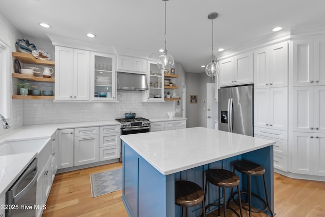188 Edgewater Cir, Sunset Beach, NC 28468 - kitchen featuring open shelves, appliances with stainless steel finishes, range hood, light wood-style floors, and a breakfast bar area