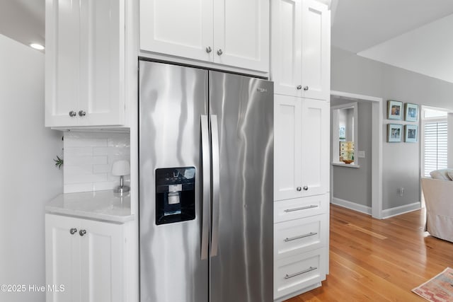 188 Edgewater Cir, Sunset Beach, NC 28468 - kitchen with stainless steel refrigerator with ice dispenser, decorative backsplash, white cabinets, and light wood-style flooring