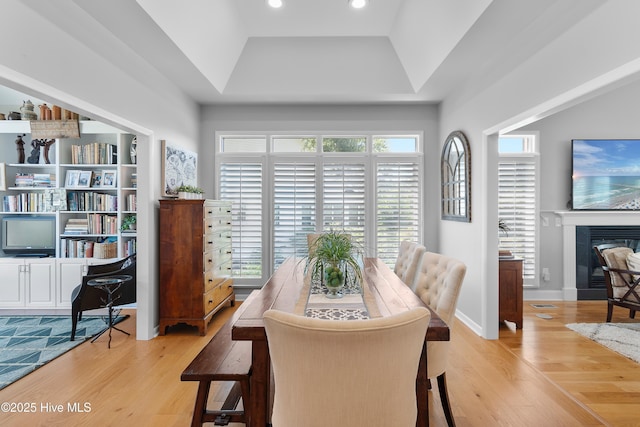 188 Edgewater Cir, Sunset Beach, NC 28468 - dining room with a raised ceiling, light wood-style flooring, a glass covered fireplace, and recessed lighting