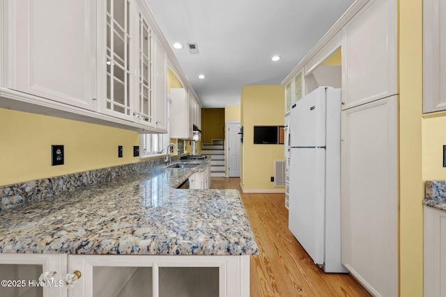 32 Windy Ct, Oriental, NC 28571 - kitchen with freestanding refrigerator, light wood finished floors, white cabinets, recessed lighting, and glass insert cabinets