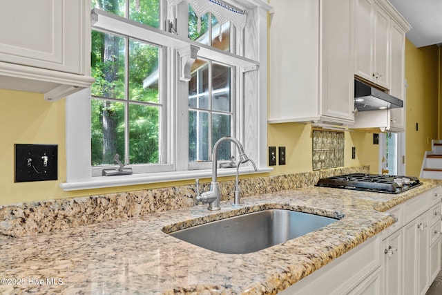 32 Windy Ct, Oriental, NC 28571 - kitchen with gas stovetop, white cabinetry, plenty of natural light, and under cabinet range hood