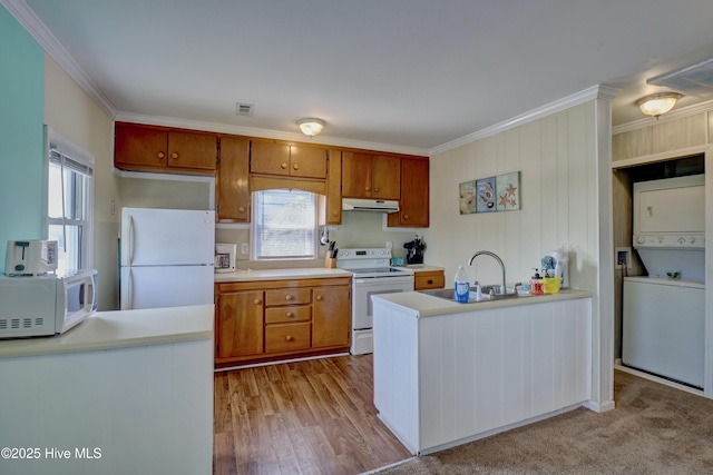 6703 13th Ave, North Topsail Beach, NC 28460 - kitchen with white appliances, under cabinet range hood, stacked washer and clothes dryer, ornamental molding, and brown cabinets