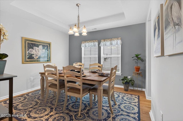 1673 White Starfish Ct, Calabash, NC 28467 - dining room featuring a tray ceiling, light wood-type flooring, and a chandelier