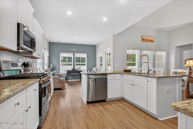 1673 White Starfish Ct, Calabash, NC 28467 - kitchen with appliances with stainless steel finishes, light wood finished floors, white cabinets, open floor plan, and light stone countertops