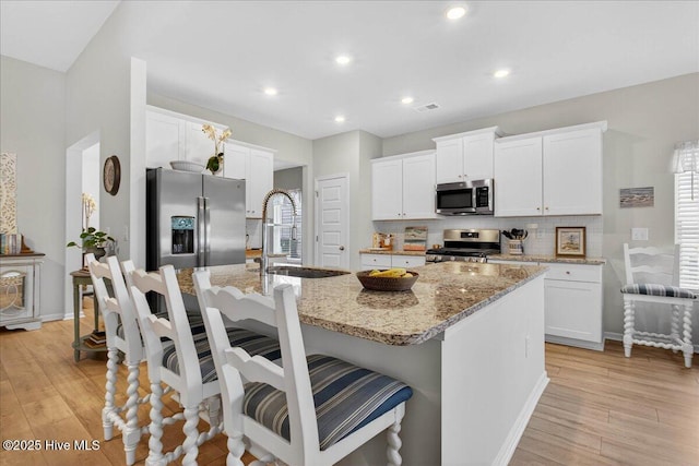 1673 White Starfish Ct, Calabash, NC 28467 - kitchen with stainless steel appliances, backsplash, light wood-style floors, white cabinets, and recessed lighting
