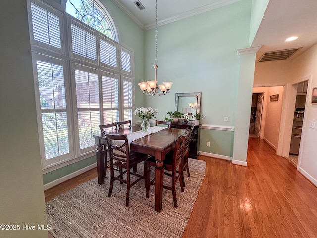 4725 Wedgefield Dr, Wilmington, NC 28409 - dining area featuring crown molding, healthy amount of natural light, light wood finished floors, a chandelier, and a high ceiling
