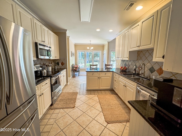 4725 Wedgefield Dr, Wilmington, NC 28409 - kitchen featuring stainless steel appliances, crown molding, decorative backsplash, a peninsula, and a chandelier