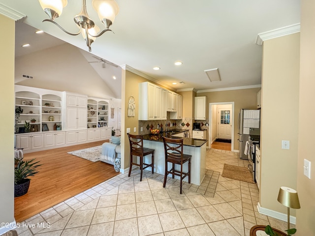 4725 Wedgefield Dr, Wilmington, NC 28409 - kitchen with crown molding, light tile patterned floors, a chandelier, a peninsula, and dark countertops