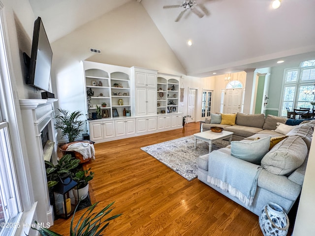 4725 Wedgefield Dr, Wilmington, NC 28409 - living area with high vaulted ceiling, light wood-type flooring, a ceiling fan, a fireplace, and ornate columns