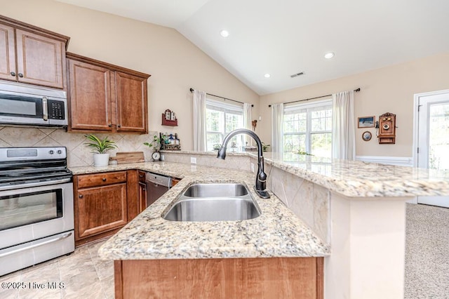 276 Widgeon Way, Lillington, NC 27546 - kitchen with appliances with stainless steel finishes, vaulted ceiling, a peninsula, light stone counters, and tasteful backsplash