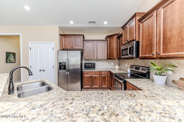 276 Widgeon Way, Lillington, NC 27546 - kitchen with appliances with stainless steel finishes, light stone countertops, backsplash, recessed lighting, and brown cabinetry