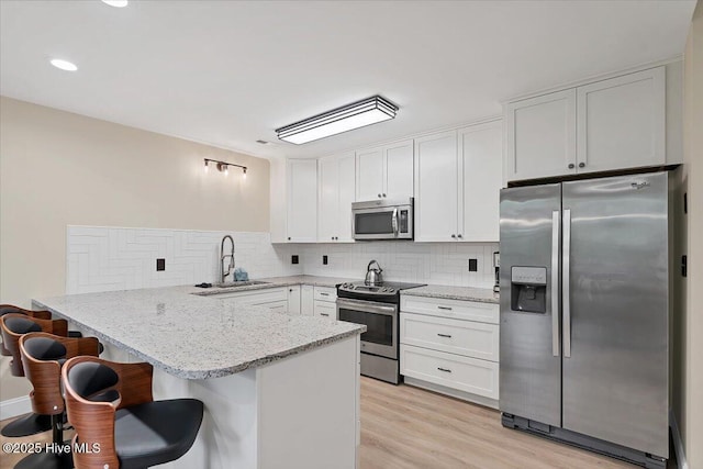 240 Cochrane Castle Cir Unit F, Pinehurst, NC 28374 - kitchen featuring appliances with stainless steel finishes, a peninsula, a breakfast bar area, decorative backsplash, and white cabinetry