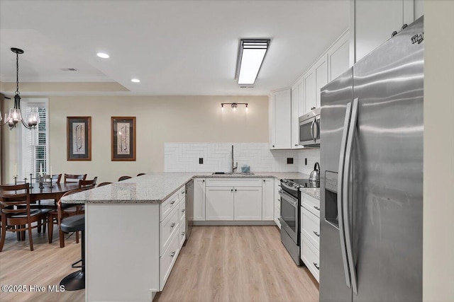 240 Cochrane Castle Cir Unit F, Pinehurst, NC 28374 - kitchen featuring stainless steel appliances, a peninsula, light wood-style flooring, white cabinetry, and decorative backsplash