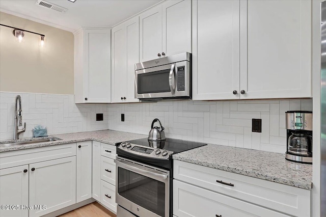 240 Cochrane Castle Cir Unit F, Pinehurst, NC 28374 - kitchen featuring stainless steel appliances, white cabinetry, decorative backsplash, and light stone counters