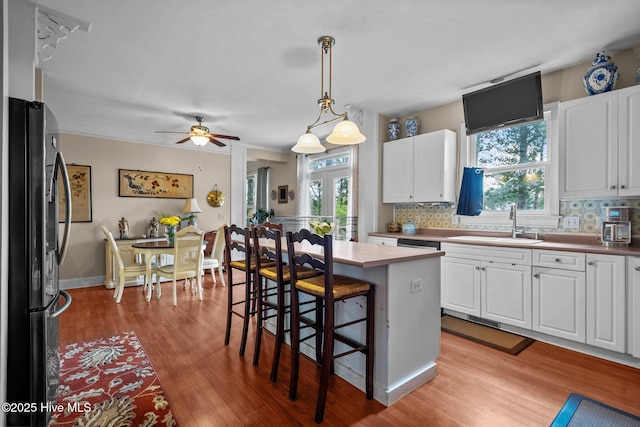 6122 Timber Creek Ln, Wilmington, NC 28411 - kitchen with freestanding refrigerator, light wood-style floors, white cabinetry, a kitchen bar, and healthy amount of natural light