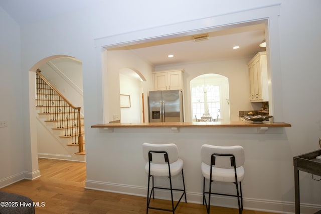 2 Tyler Way, Pinehurst, NC 28374 - kitchen with stainless steel fridge, wood finished floors, arched walkways, a breakfast bar area, and a peninsula