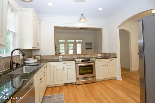 2 Tyler Way, Pinehurst, NC 28374 - kitchen with stainless steel appliances, arched walkways, backsplash, light wood-style flooring, and ornamental molding