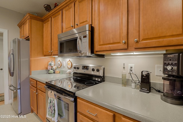 1045 Edenton Dr NW, Calabash, NC 28467 - kitchen with appliances with stainless steel finishes, brown cabinetry, light tile patterned floors, and light countertops