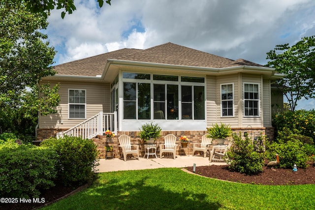 1045 Edenton Dr NW, Calabash, NC 28467 - rear view of house featuring a patio area, a yard, roof with shingles, a sunroom, and stone siding