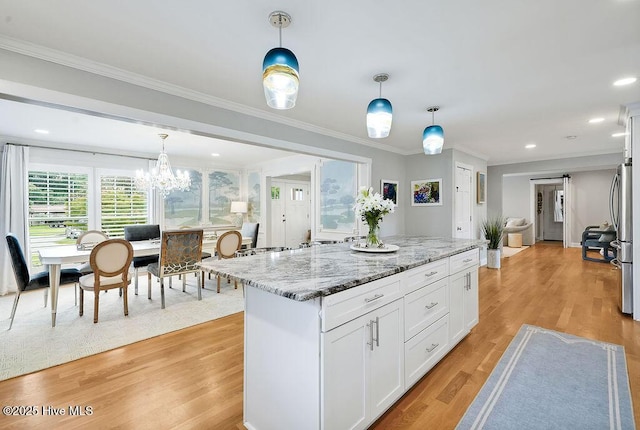 311 Lennox Pl, Wilmington, NC 28412 - kitchen featuring light stone counters, white cabinets, crown molding, decorative light fixtures, and a kitchen island
