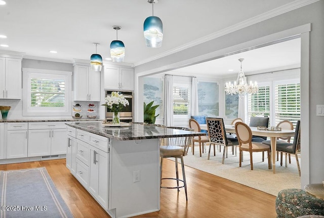 311 Lennox Pl, Wilmington, NC 28412 - kitchen with light wood finished floors, double oven, a breakfast bar area, a center island, and backsplash