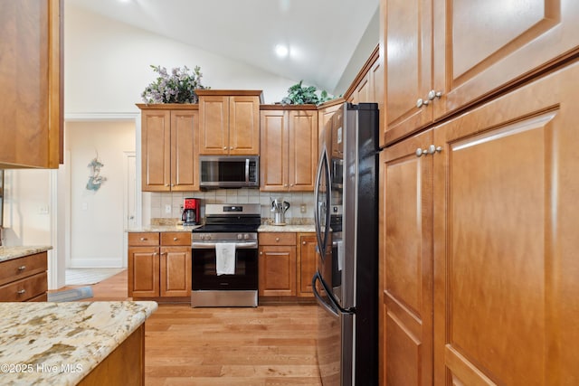 258 Morning View Way, Leland, NC 28451 - kitchen featuring appliances with stainless steel finishes, tasteful backsplash, light wood finished floors, vaulted ceiling, and brown cabinets
