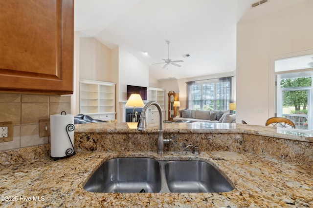 258 Morning View Way, Leland, NC 28451 - kitchen with light stone counters, a ceiling fan, brown cabinets, open floor plan, and high vaulted ceiling