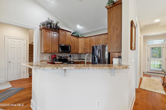 258 Morning View Way, Leland, NC 28451 - kitchen featuring appliances with stainless steel finishes, light wood-style flooring, a kitchen bar, decorative backsplash, and light stone counters