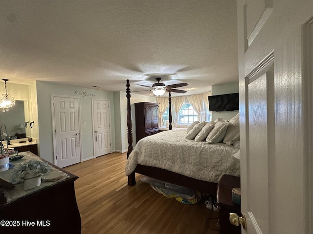 2270 Bella Coola Rd, Lake Waccamaw, NC 28450 - bedroom with light wood finished floors, a chandelier, a textured ceiling, and a ceiling fan