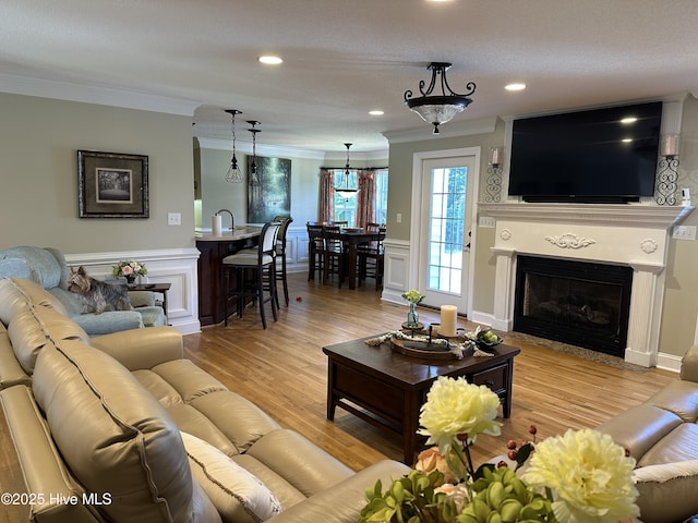 2270 Bella Coola Rd, Lake Waccamaw, NC 28450 - living area with ornamental molding, a decorative wall, light wood finished floors, a glass covered fireplace, and a wainscoted wall