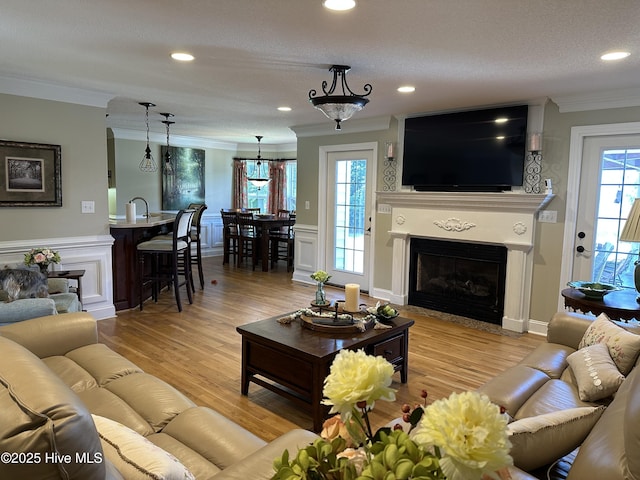 2270 Bella Coola Rd, Lake Waccamaw, NC 28450 - living area featuring ornamental molding, a fireplace with flush hearth, a decorative wall, a wainscoted wall, and light wood-style floors