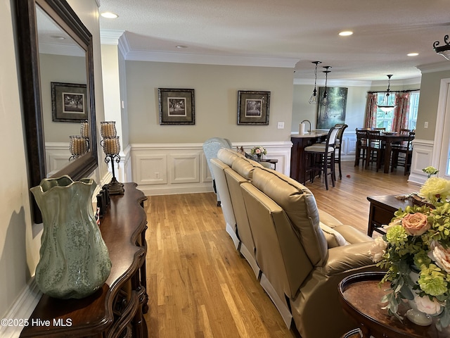 2270 Bella Coola Rd, Lake Waccamaw, NC 28450 - living room with crown molding, wainscoting, light wood-style flooring, a decorative wall, and recessed lighting