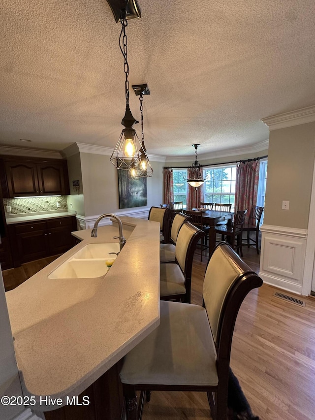 2270 Bella Coola Rd, Lake Waccamaw, NC 28450 - dining area featuring crown molding, wood finished floors, a textured ceiling, and a wainscoted wall