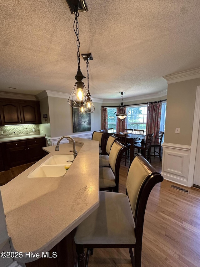 2270 Bella Coola Rd, Lake Waccamaw, NC 28450 - dining area with ornamental molding, wood finished floors, a textured ceiling, and a wainscoted wall