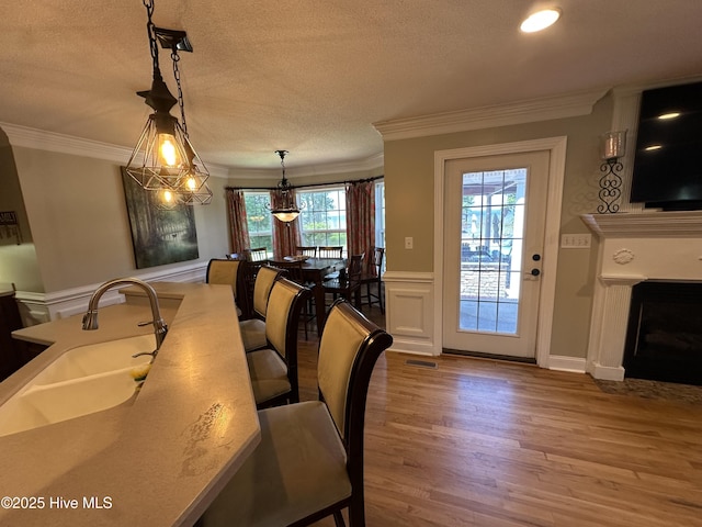 2270 Bella Coola Rd, Lake Waccamaw, NC 28450 - dining room with wood finished floors, crown molding, healthy amount of natural light, a fireplace, and a textured ceiling