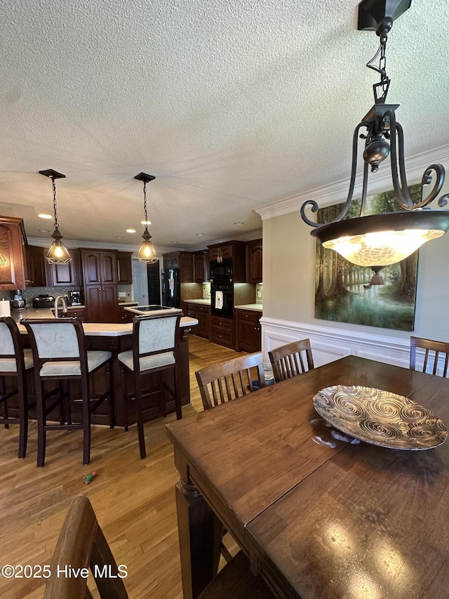 2270 Bella Coola Rd, Lake Waccamaw, NC 28450 - dining space with light wood-style floors, a textured ceiling, and crown molding