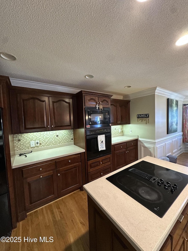 2270 Bella Coola Rd, Lake Waccamaw, NC 28450 - kitchen featuring black appliances, light countertops, a textured ceiling, ornamental molding, and wood finished floors