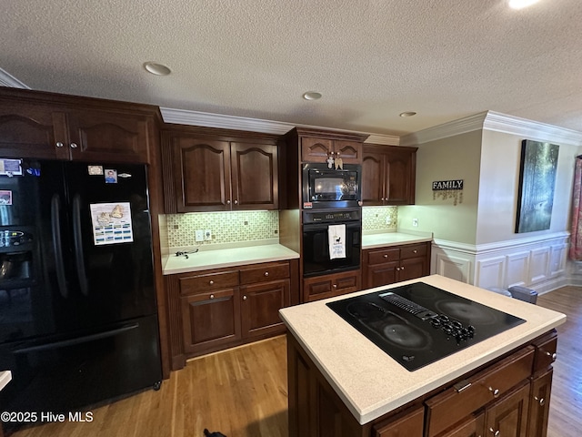 2270 Bella Coola Rd, Lake Waccamaw, NC 28450 - kitchen with black appliances, light countertops, light wood-type flooring, crown molding, and backsplash
