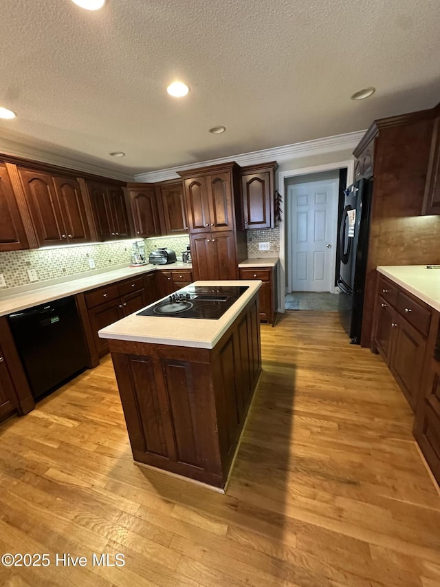 2270 Bella Coola Rd, Lake Waccamaw, NC 28450 - kitchen featuring black appliances, a textured ceiling, light countertops, a center island, and decorative backsplash