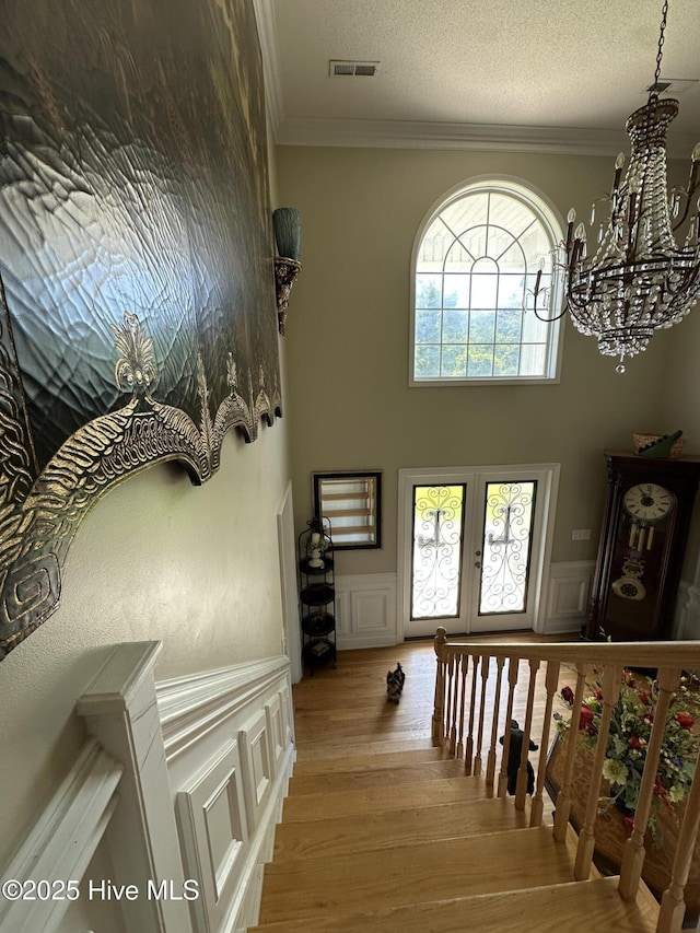 2270 Bella Coola Rd, Lake Waccamaw, NC 28450 - hallway featuring a decorative wall, a chandelier, ornamental molding, wood finished floors, and wainscoting