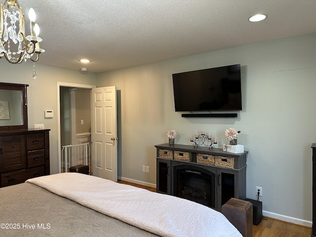 2270 Bella Coola Rd, Lake Waccamaw, NC 28450 - bedroom with wood finished floors, recessed lighting, a fireplace, a chandelier, and a textured ceiling
