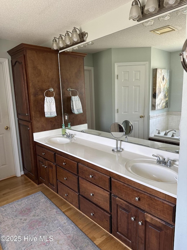 2270 Bella Coola Rd, Lake Waccamaw, NC 28450 - bathroom featuring wood finished floors, double vanity, a textured ceiling, and a bathtub