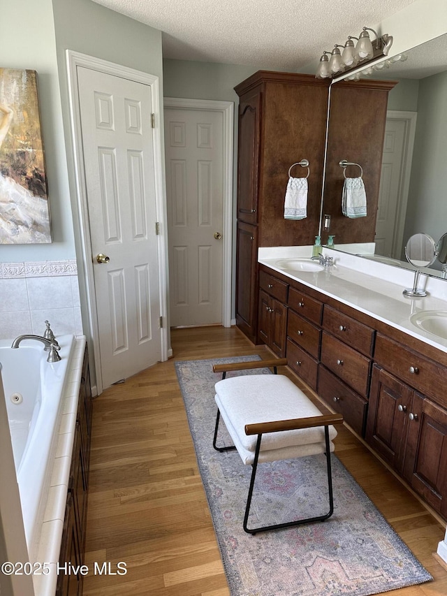 2270 Bella Coola Rd, Lake Waccamaw, NC 28450 - full bath featuring wood finished floors, double vanity, a whirlpool tub, and a textured ceiling