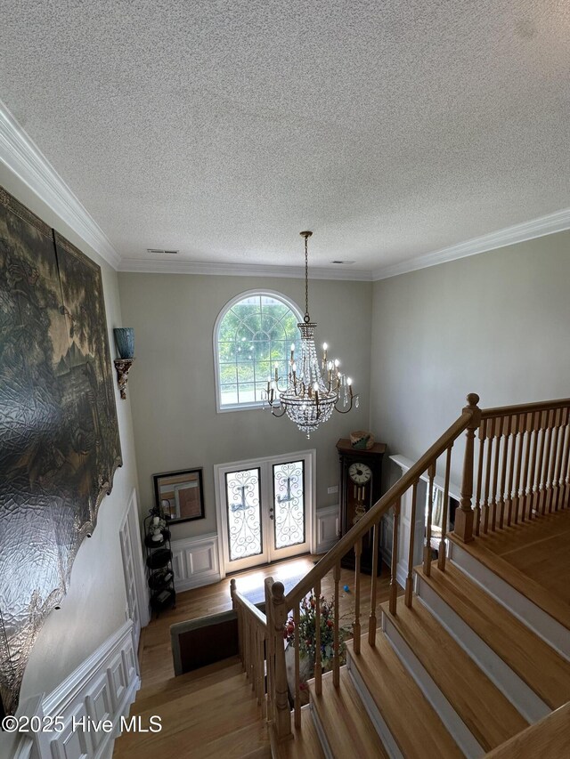 2270 Bella Coola Rd, Lake Waccamaw, NC 28450 - staircase with wood finished floors, a chandelier, ornamental molding, a textured ceiling, and wainscoting