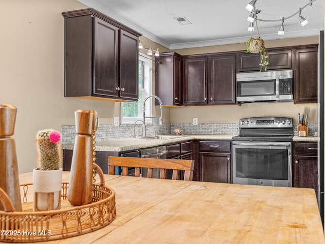 165 Parnell Rd, Hubert, NC 28539 - kitchen featuring appliances with stainless steel finishes, dark brown cabinetry, crown molding, tasteful backsplash, and track lighting