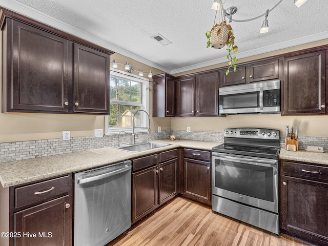 165 Parnell Rd, Hubert, NC 28539 - kitchen with stainless steel appliances, a textured ceiling, light wood finished floors, dark brown cabinetry, and crown molding