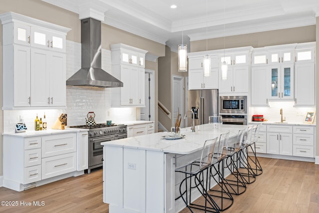 805 Wild Turkey Pl, Wilmington, NC 28405 - kitchen featuring wall chimney range hood, premium appliances, light wood-style floors, a kitchen bar, and an island with sink